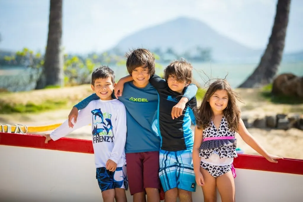 Kids smiling for photo with arms linked at Kahala Beach